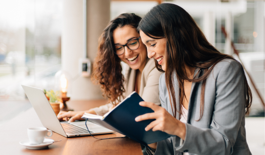 Deux professionnelles souriantes analysent un document devant un ordinateur portable, illustrant la collaboration autour de la minimisation des données.